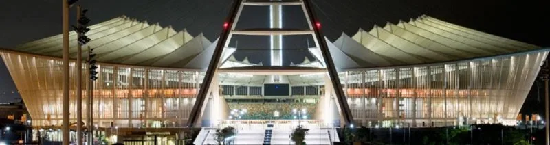 Moses Mabhida Stadium lit up at night, its arch rising over the entrance