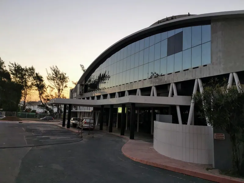 The curved glass front and entrance canopy of the Olive Convention Centre in Durban at dusk
