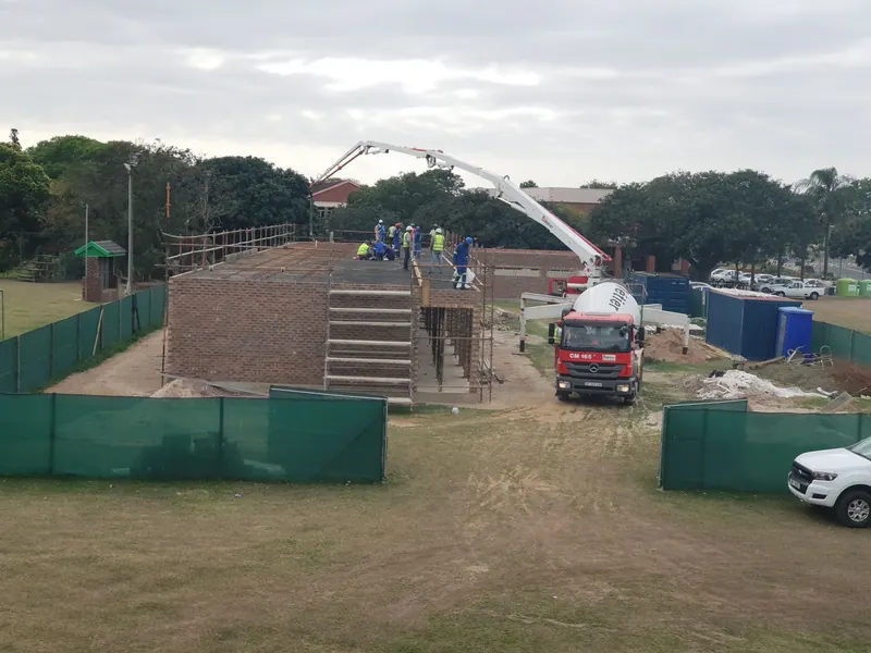 A concrete pump truck and site hoarding beside the raised brick stand under construction at Pitlochry