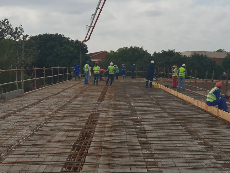 Workers in hard hats on a reinforced concrete slab before the pour at Pitlochry, a concrete pump boom overhead